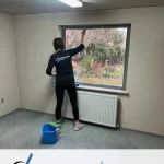 Kvindelig medarbejder fra Midtjysk Facility Service pudser vinduer.